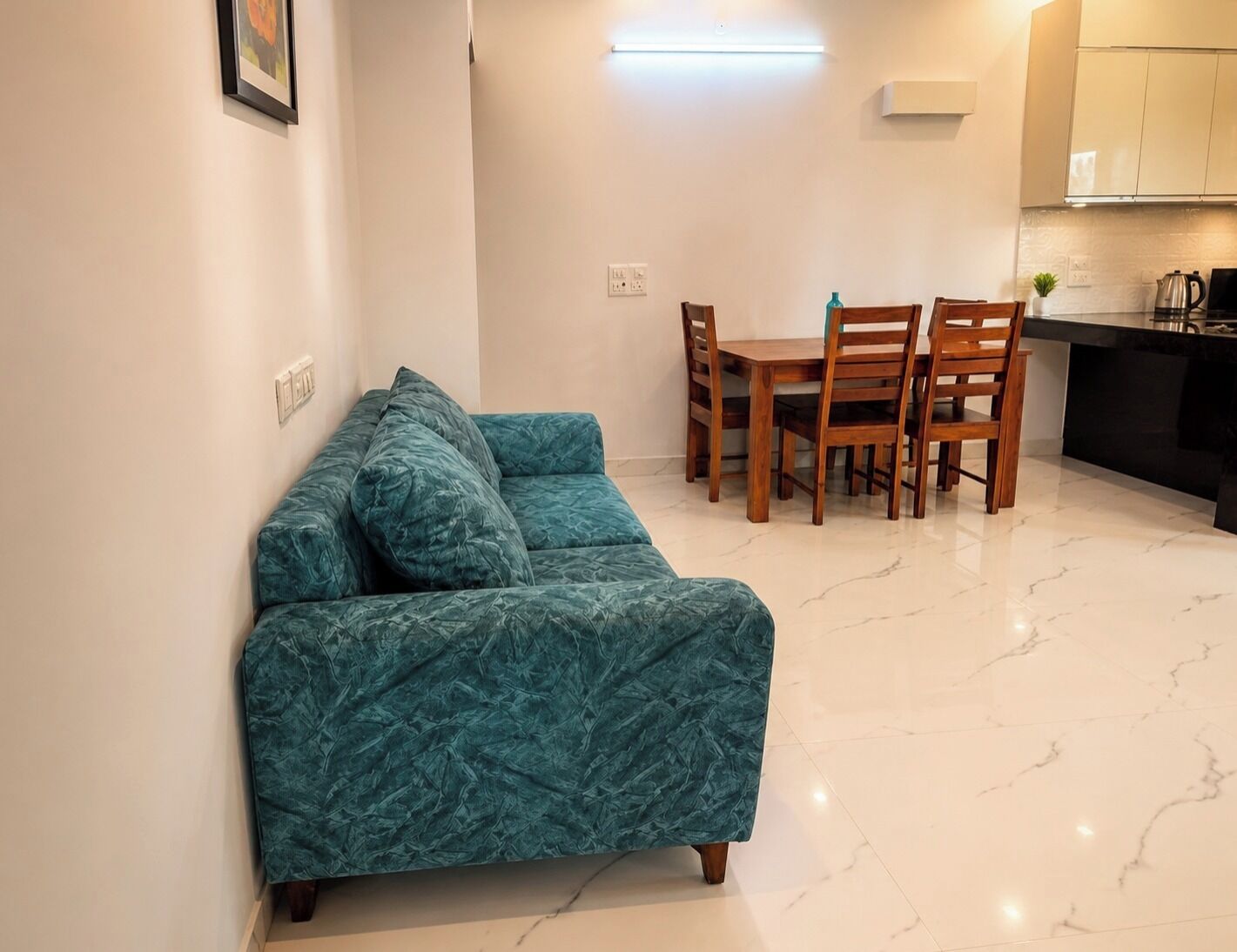 A compact living space with a sofa, a dining table with chairs, and a kitchen area.