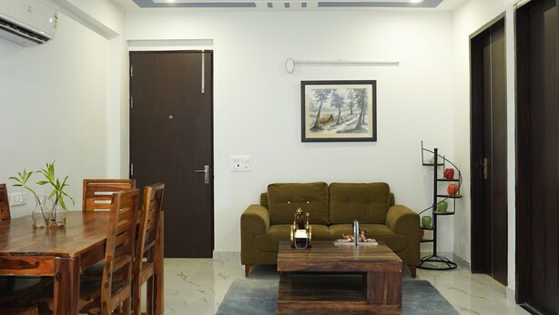 A living room with a dining area, a sofa, a coffee table, and a ceiling fan. - Lime Tree 2Bhk Serviced Apartment (Gurugram)