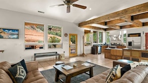 A spacious living room with a large sofa, a coffee table, and a view of a desert landscape through large windows.