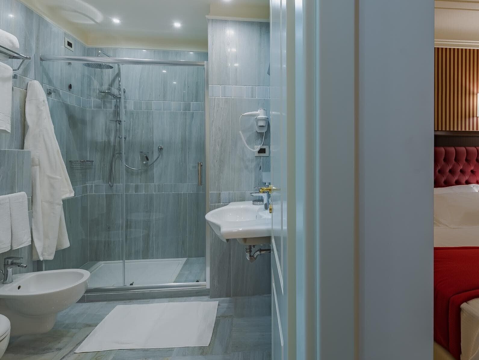 A modern bathroom with a glass-enclosed shower, a white sink, and a bidet.
