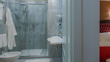 A modern bathroom with a glass-enclosed shower, a white sink, and a bidet.