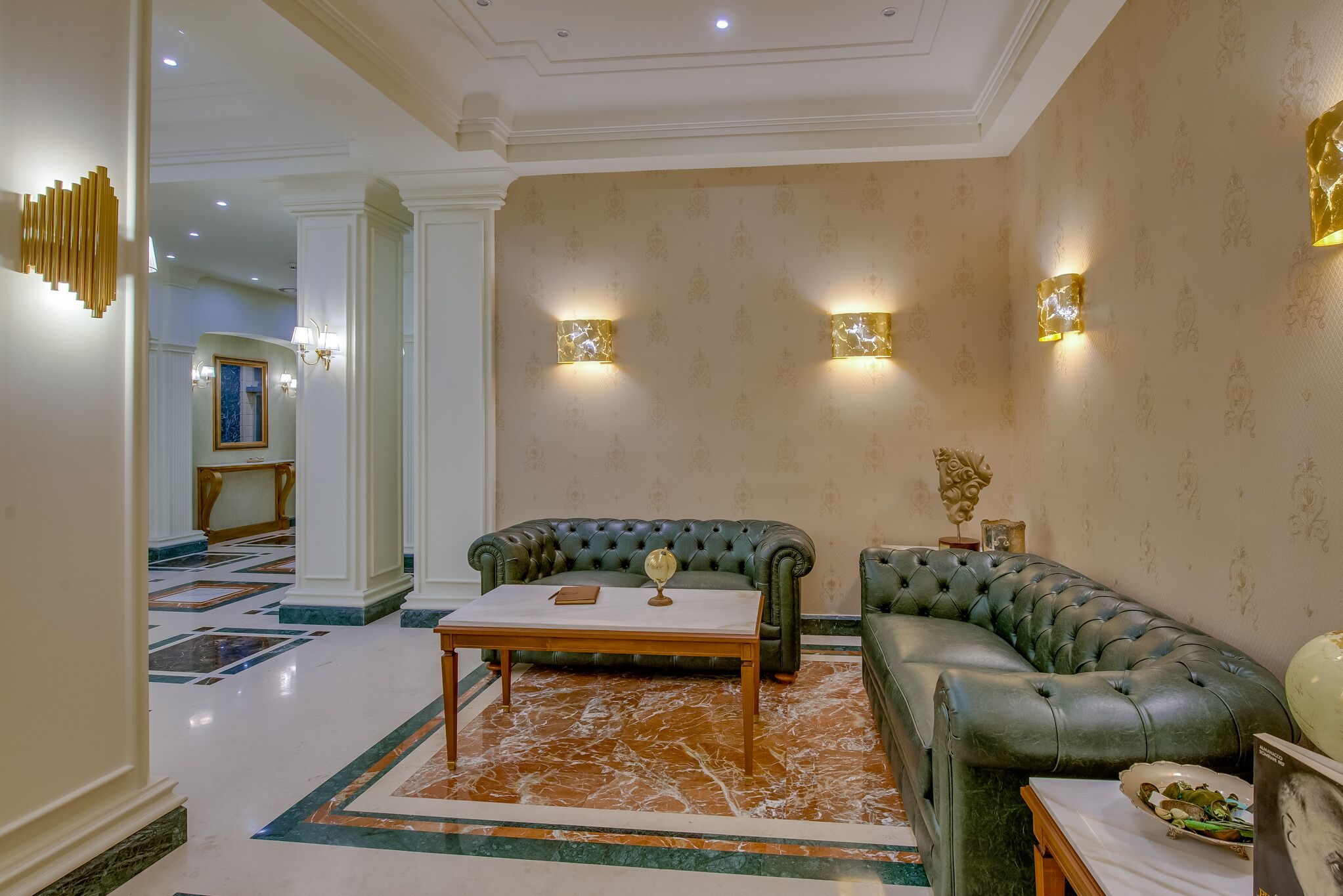 A luxurious living room with a green leather sofa, a wooden coffee table, and a patterned rug.