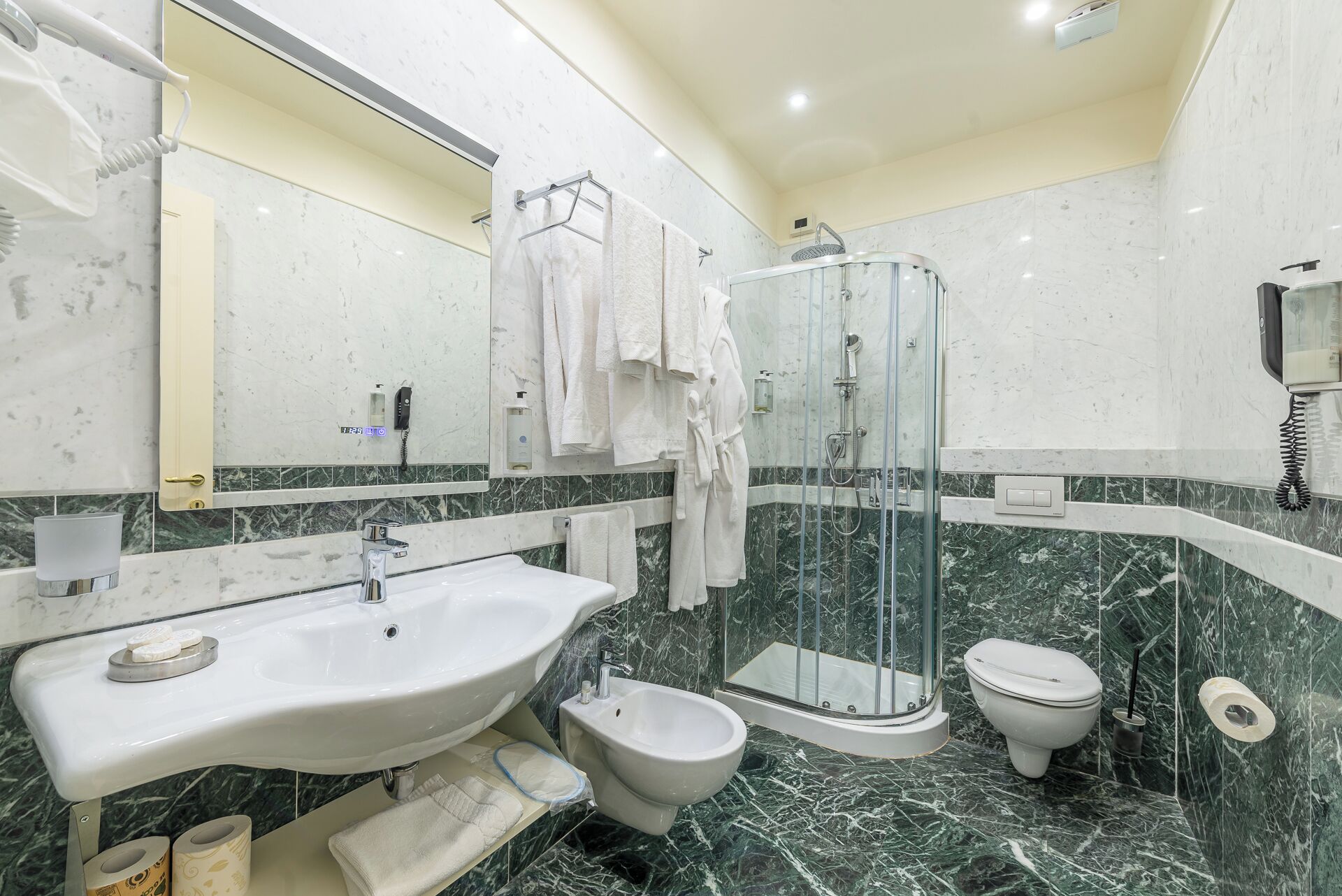 A modern bathroom with a large sink, bidet, toilet, and a glass-enclosed shower.