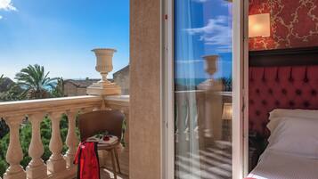 Une chambre d’hôtel avec balcon, un lit doté d’une tête de lit rouge et une vue sur la mer.