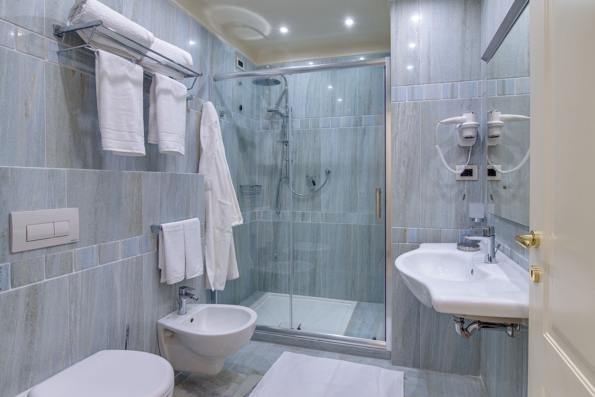 A modern bathroom with a glass-enclosed shower, a bidet, a sink, and a toilet.