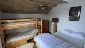 A bedroom with a bunk bed, a single bed, a wooden ceiling, a white furry rug, and a wall-mounted lamp. - Apartment in Le Sauze with unobstructed mountain views (Enchastrayes)