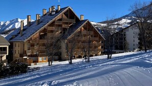A ski resort with wooden buildings, snow-covered slopes, and mountains in the background. - Apartment in Le Sauze with unobstructed mountain views (Enchastrayes)