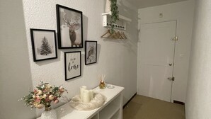 A hallway with a white console table, framed pictures, a potted plant, and a door. - Apartment in Le Sauze with unobstructed mountain views (Enchastrayes)