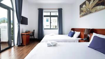 A hotel room with two beds, a desk, a chair, a TV, and a window with curtains.