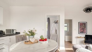 Una cocina moderna con encimera blanca, microondas y comedor con mesa de mármol.