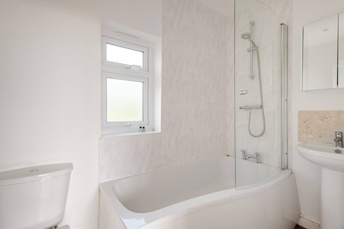 A modern bathroom with a bathtub, a shower, a window, and a sink.