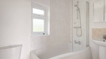 A modern bathroom with a bathtub, a shower, a window, and a sink.