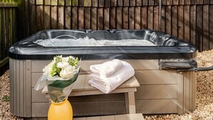 Un jacuzzi con cubierta de madera, un ramo de flores y una pila de toallas.