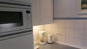 Una cocina con microondas, cafetera y un cuadro en la pared.