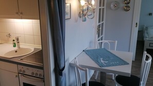 Una cocina compacta con horno Bosch, un lavamanos y un pequeño comedor con mesa y sillas.