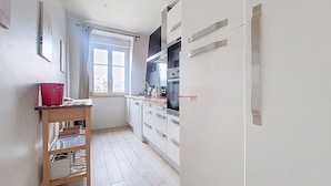 Una cocina estrecha con armarios blancos, una mesa de madera y una ventana con vistas.