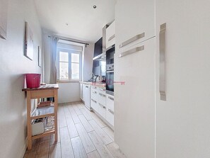 Una cocina estrecha con armarios blancos, una mesa de madera y una ventana con vistas.