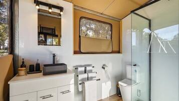 A modern bathroom with a white vanity, a mirror, a window, and a glass shower enclosure.