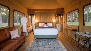 A tented room with a bed, a sofa, a table, and a ceiling fan.