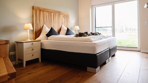 Une chambre à coucher moderne avec un grand lit, une table de chevet et une fenêtre donnant sur l’extérieur.