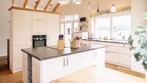 Une cuisine moderne avec des meubles blancs, un plan de travail en granit et des luminaires suspendus.