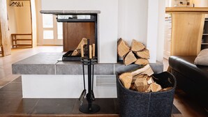 Une cuisine moderne dotée d’une cuisinière intégrée, d’un support en métal noir avec un plateau en verre et d’un panier de bois de chauffage.