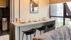Une cuisine moderne dotée d’un plan de travail en marbre, d’une machine à café et d’un coin bar avec des tabourets.