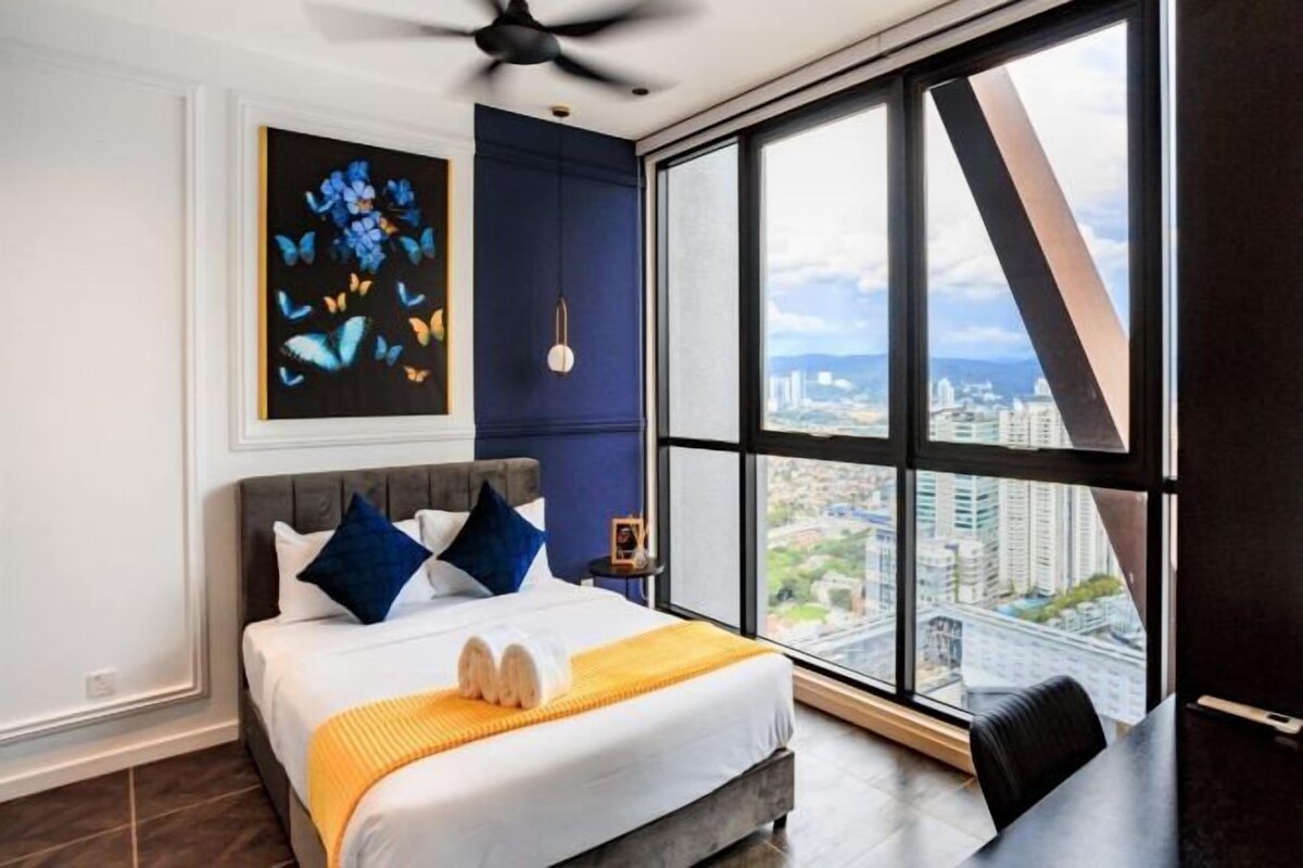 Une chambre d’hôtel moderne avec un grand lit, une vue sur la ville et un ventilateur de plafond.