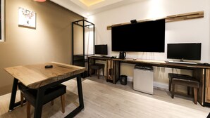 A modern kitchen with a wooden table, two bar stools, a built-in dishwasher, and a large flat-screen TV mounted on the wall. - The Stay Series (Daegu)