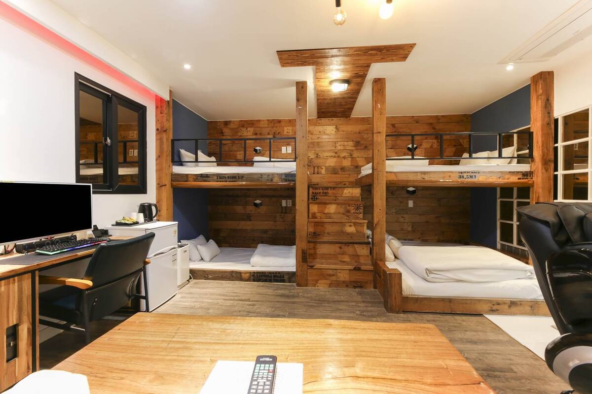 A compact room with bunk beds, a desk with a computer, and a chair.