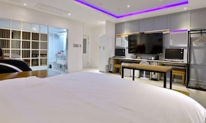Relax in this spacious room featuring a large bed, kitchenette with microwave and flat-screen TV, and a walk-in closet.