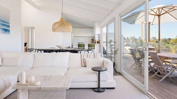Un salon moderne avec un canapé blanc, une table basse ronde et un coin repas comprenant une table et des chaises.