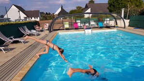 En pool med liggestole og et overdækket område.