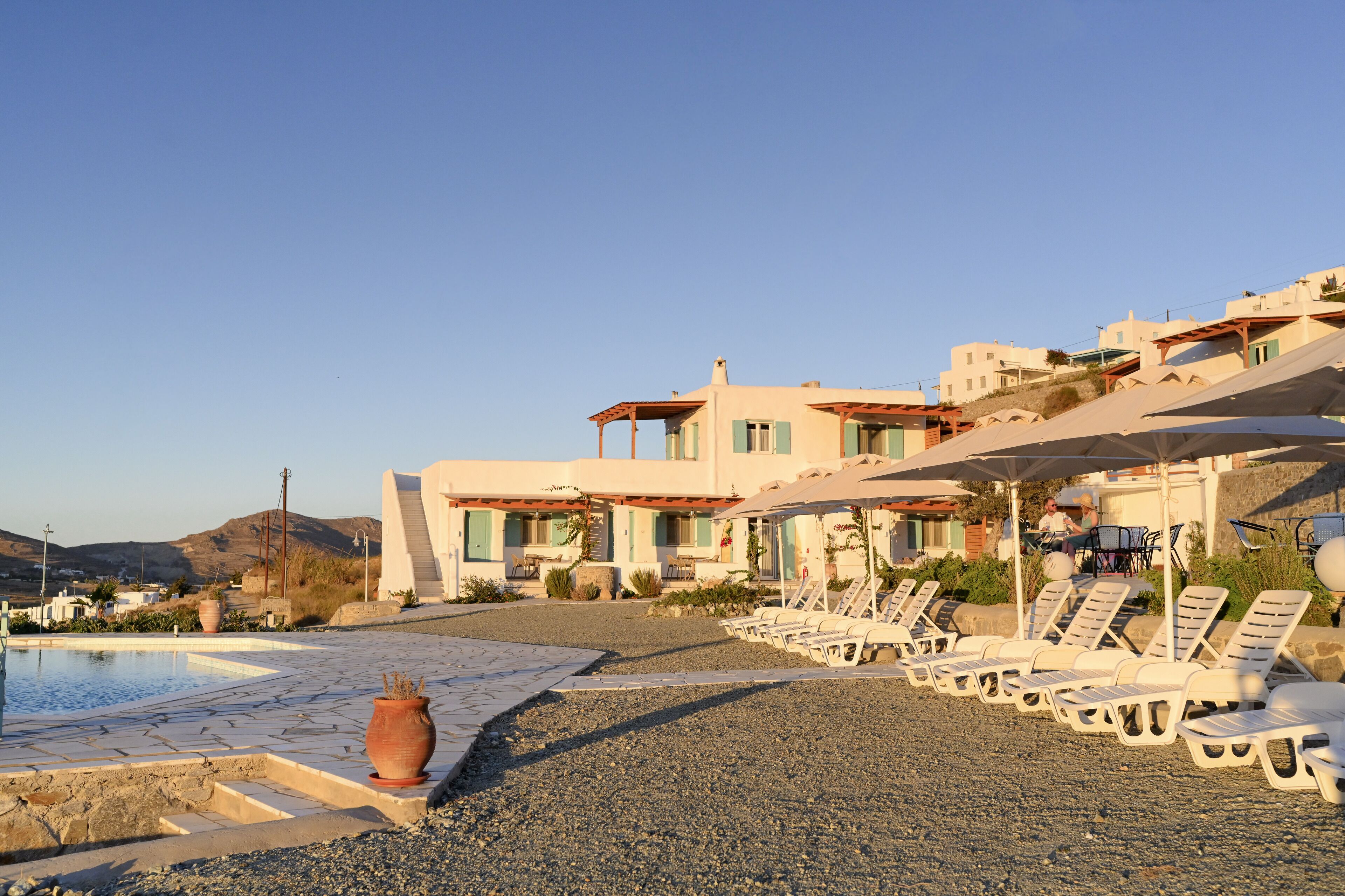 A modern resort with a pool, lounge chairs, and a building with multiple balconies.