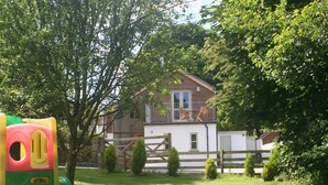 A house with a balcony, surrounded by a wooden fence and small trees. - Luxury child and baby friendly rural retreat. Close to Porthleven and St Ives (Helston)