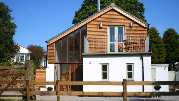 A modern house with a large glass window, a wooden deck, and a green door. - Luxury child and baby friendly rural retreat. Close to Porthleven and St Ives (Helston)