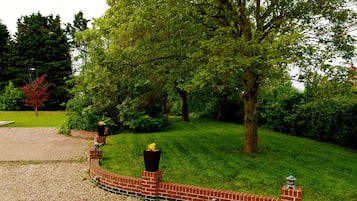 A landscaped garden with a brick wall, trees, and a gravel path.
