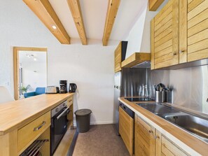 Una cucina compatta con mobili in legno, un lavello in acciaio inossidabile e un piccolo cestino.