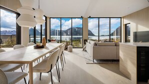 A modern interior with a dining area, sofa, and large windows offering a mountain view. - NEW! Luxury Cabin in beautiful Lofoten (Nordland)