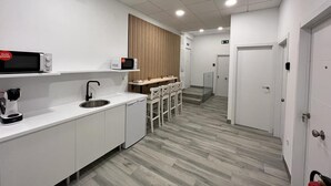 Una cocina moderna con armarios blancos, microondas, cafetera y panel de pared de madera.