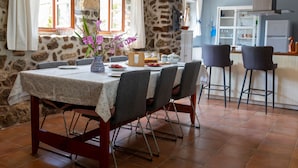 Uma área de refeições com parede de pedra, uma mesa com toalha florida e cadeiras.