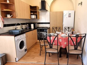Une cuisine compacte équipée d’un lave-linge, d’une table à manger pour quatre personnes et d’un réfrigérateur.