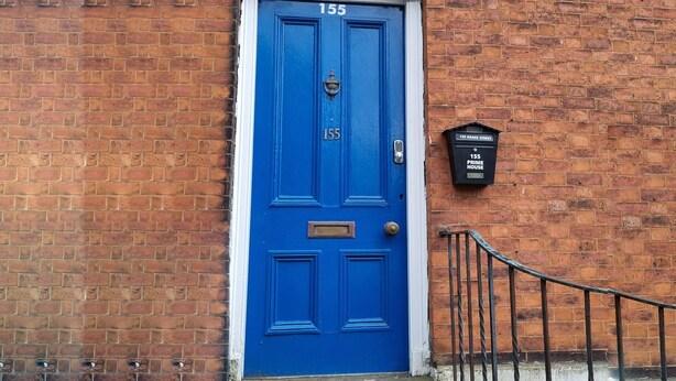 Una porta blu con il numero 155, una cassetta postale e una ringhiera metallica.