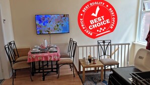 Zona pranzo con tavolo apparecchiato per quattro persone, televisione montata a parete e adesivo rosso con la scritta "Best Choice".