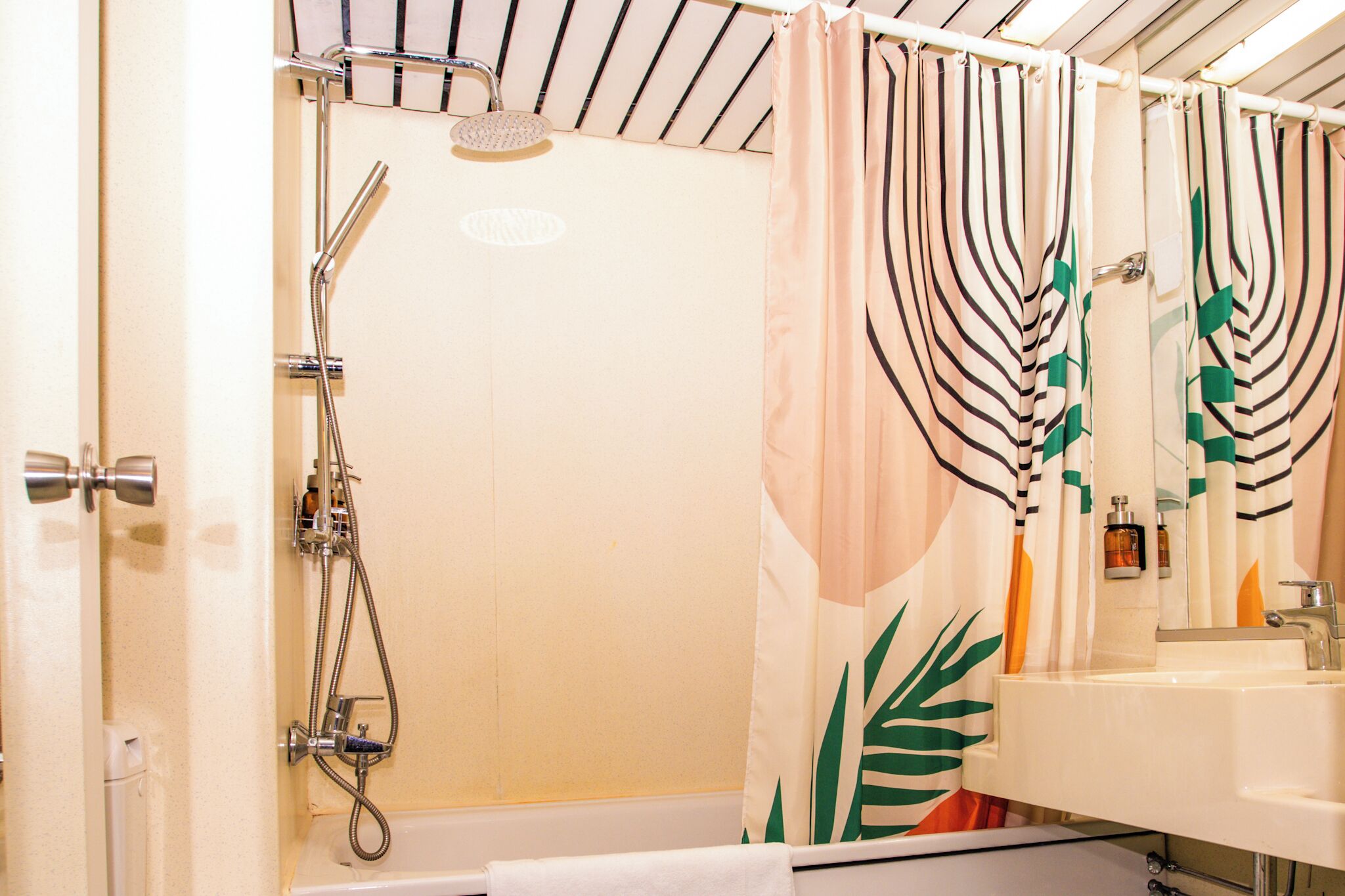 Un baño con ducha, lavamanos y espejo.