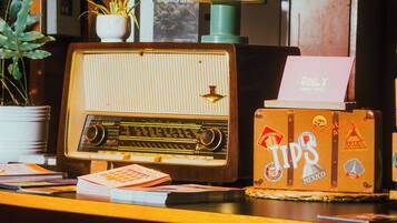 Una radio antigua, una pila de revistas y una maleta con pegatinas de viaje sobre una encimera de madera.