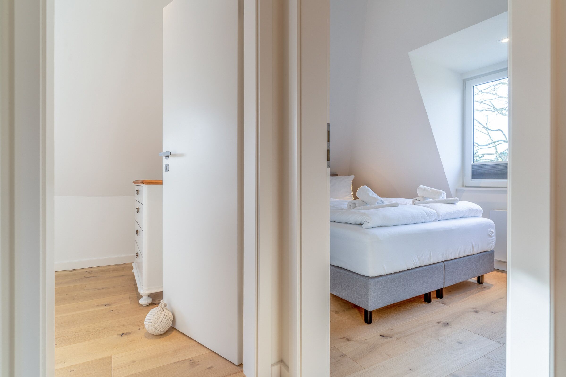 A bedroom with a bed, a bedside table, and a window.