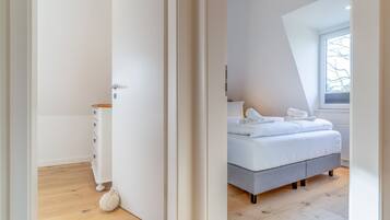 A bedroom with a bed, a bedside table, and a window.