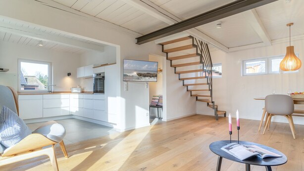 Un vaste espace de vie comprenant un escalier en bois, un coin repas et une cuisine.