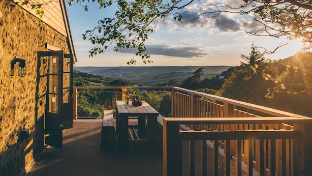 Une terrasse en bois avec une table et des chaises, offrant une vue sur un paysage magnifique.